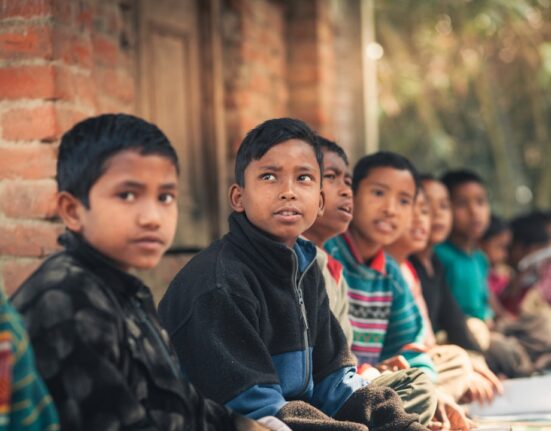 Niños sentados al aire libre aprendiendo juntos, educación inclusiva