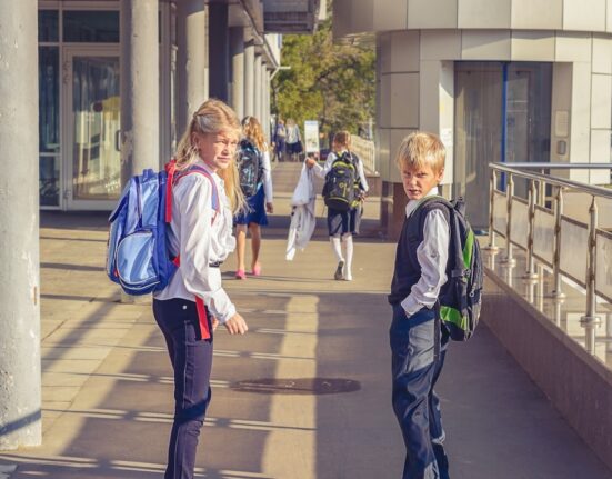 Dos estudiantes con mochilas camino a la escuela durante el regreso a clases